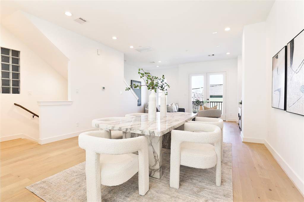 Soaring ceilings are illuminated by natural light streaming through floor-to-ceiling windows. White Oak flooring extends throughout the home, offering a warm, inviting, and sophisticated space to gather.