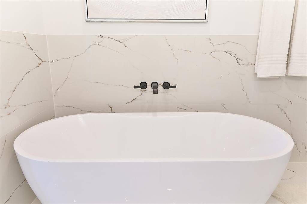 Expansive porcelain tiles enhance the bathroom's elegance, creating a serene, spa-like retreat perfect for relaxation.