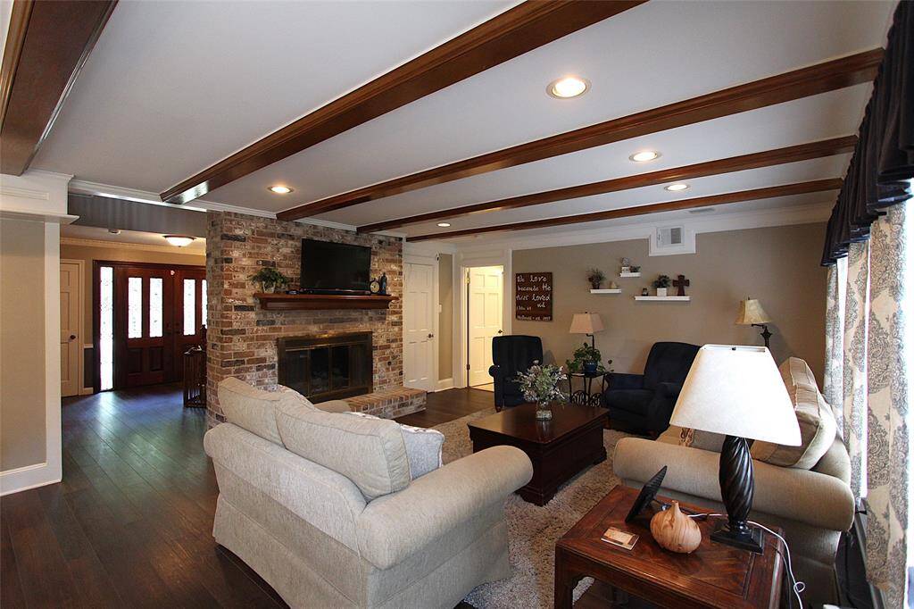 Den has recessed lighting, luxury vinyl plank flooring, and windows that look out into the back yard