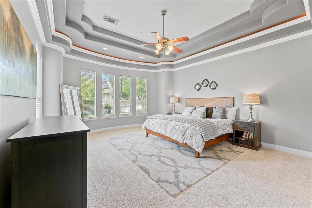 The luxurious primary retreat boasts tray ceilings, generous windows for natural light, and ample space for relaxation. Not the elegant ceiling detail.