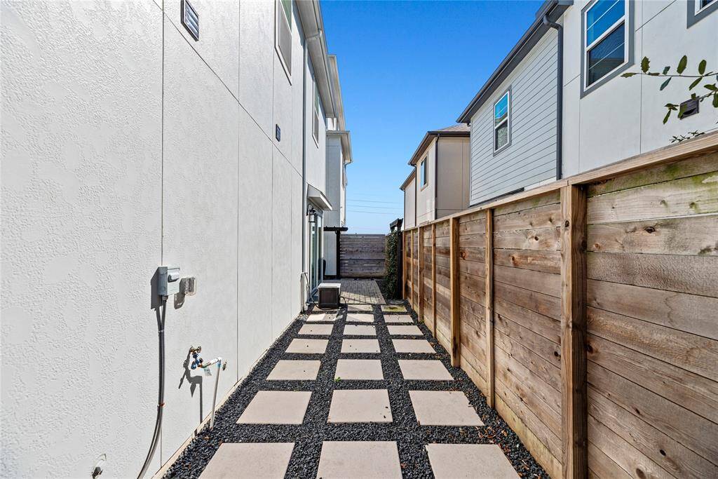 The paved pathway running alongside the fence offers an ideal space for showcasing potted plants, adding a touch of greenery and charm to the surroundings