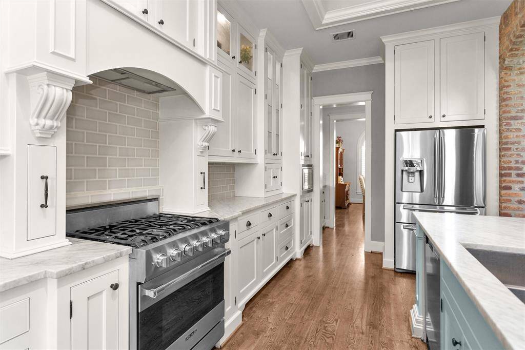 The chef’s kitchen offers sleek Carrera marble countertops, stainless steel appliances, a freestanding range, ample cabinetry, and a breakfast bar—where luxury meets function.