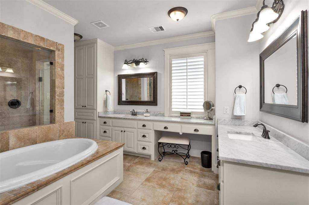 Spa-like luxury with double sinks, a jetted tub, an oversized walk-in shower, and plenty of storage—comfort and elegance in one space.