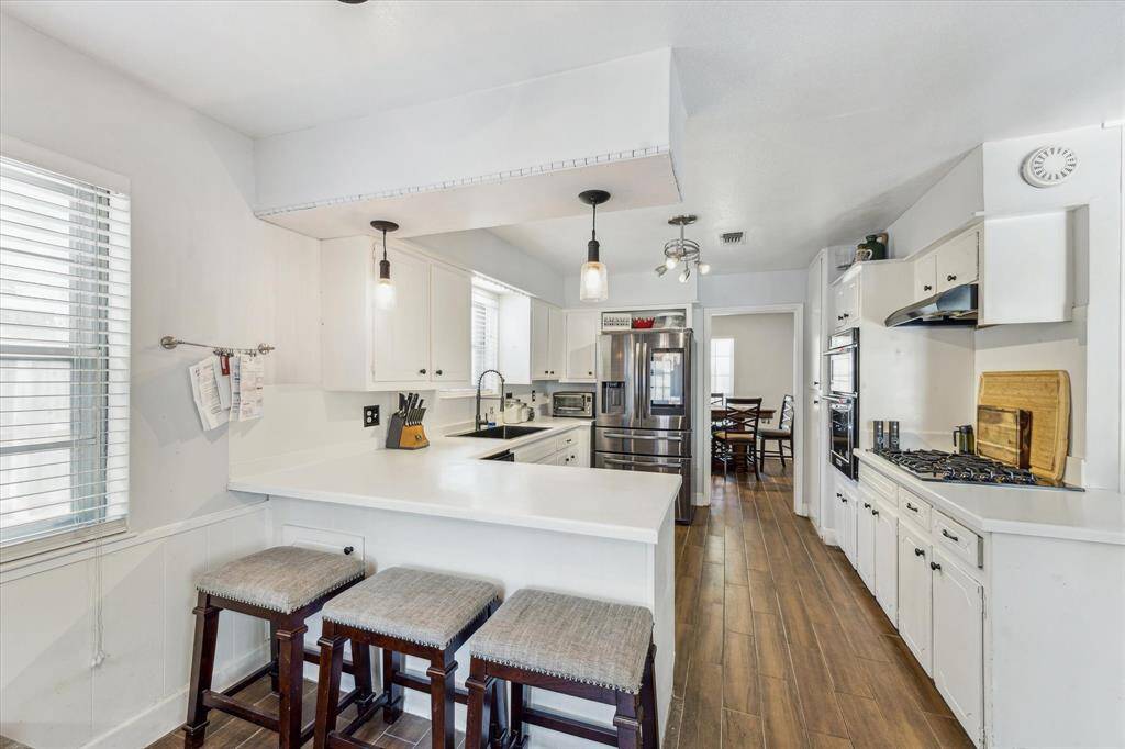 This bright, white kitchen boasts quartz countertops, stainless steel appliances, and a gas cooktop for a modern cooking experience!