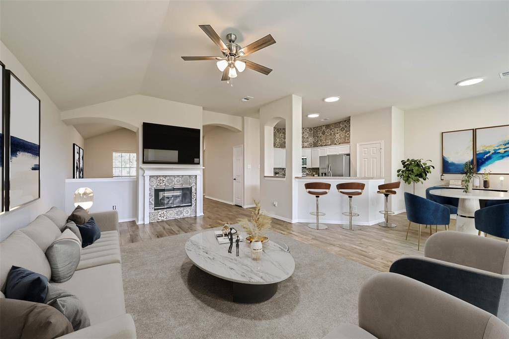Living room open to the kitchen features a double sided fireplace, high ceilings and an abundance of windows infusing the home with morning light