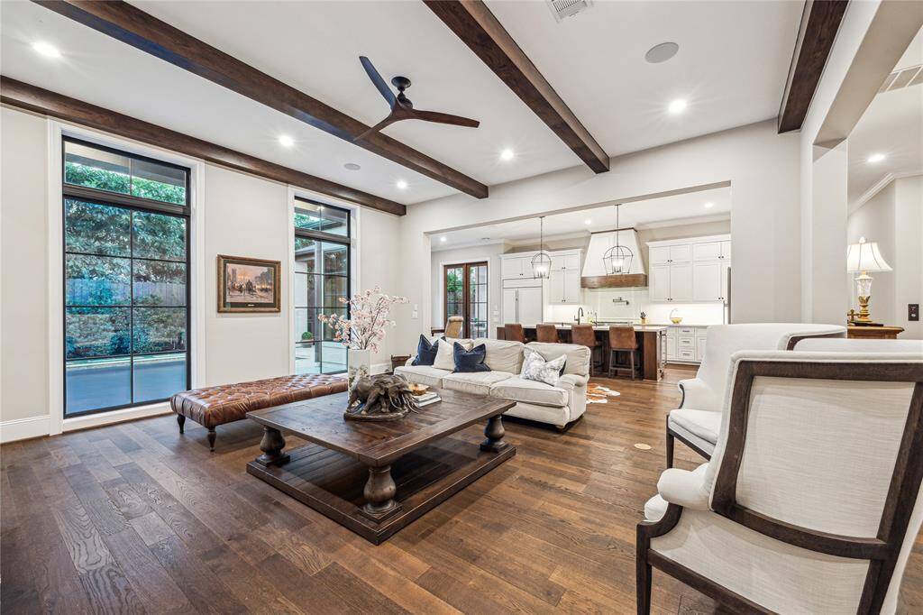 This spacious family room boasts double floor-to-ceiling windows that frame a stunning view of the pool, filling the space with natural light.