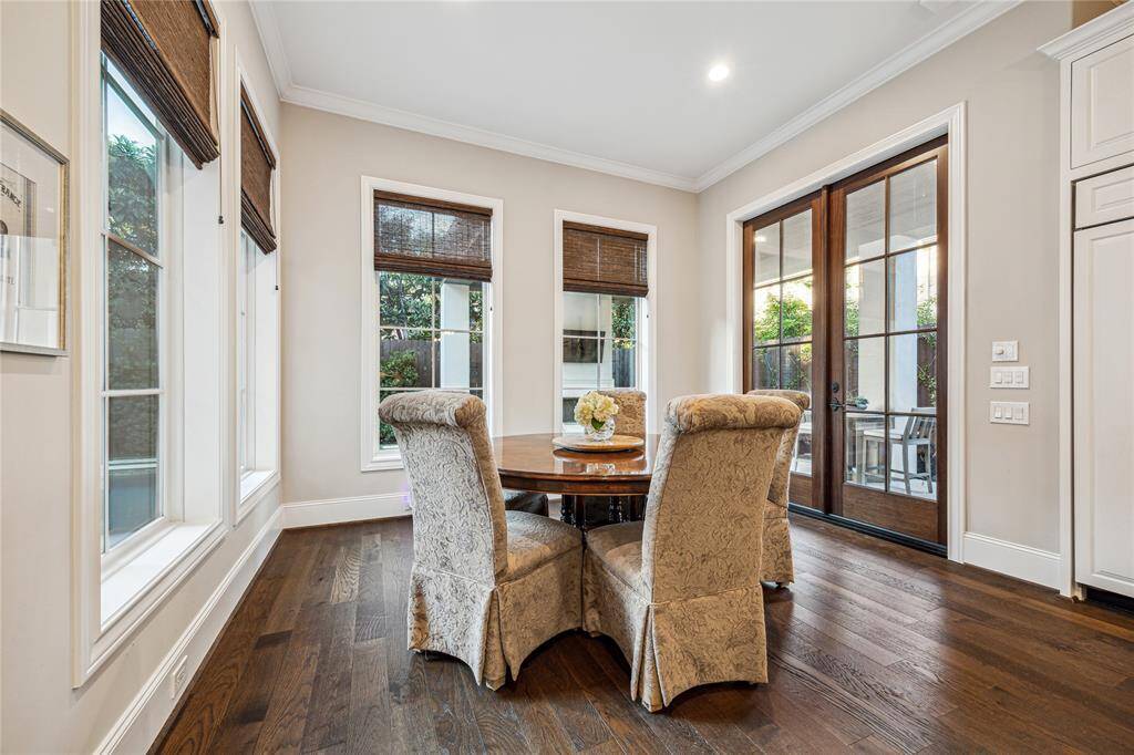 The cozy breakfast nook features woven shades and offers a peaceful spot to enjoy meals with a view of the pool. Its open layout allows for a casual dining experience, seamlessly connecting to the kitchen and family room, with double doors providing direct access to the pool and outdoor kitchen.