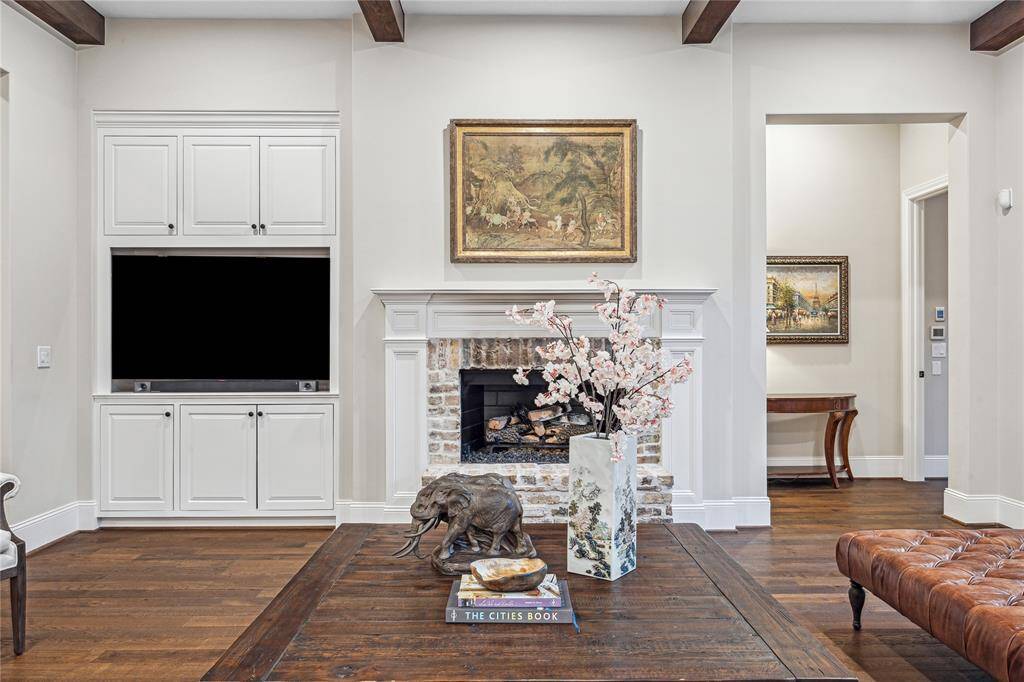 A true testament to craftsmanship, this family room features detailed wood beams on the ceiling, a custom brick fireplace, and built-ins that enhance the room’s character while offering practical storage for modern living.