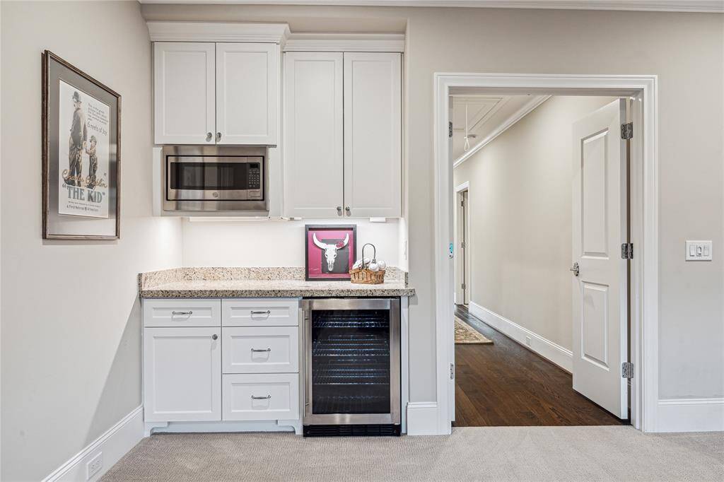 The stylish dry bar is equipped with a beverage fridge, granite countertops, and custom cabinetry for both upper and lower storage.