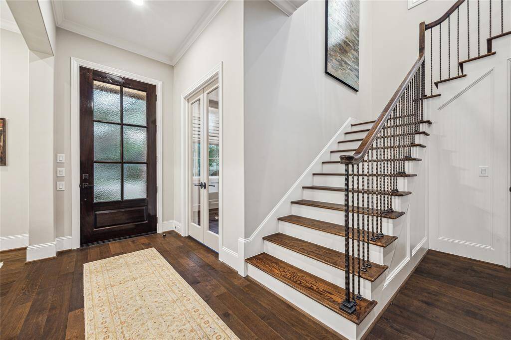 Elegant foyer featuring a staircase with iron spindles and wood railing, and a view into the study through double French glass doors just off the entry.