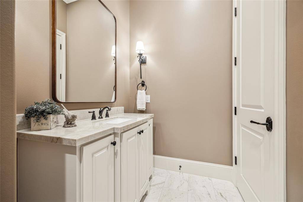 The elegant powder room features marble tile flooring and a custom vanity, creating a sophisticated atmosphere. With a Toto washlet toilet and modern fixtures. Located near laundry room.