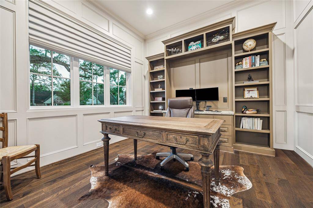 Warm and inviting, the study features rich wood paneling, built-in wall shelving, and glass-paned French doors. Large Anderson windows fill the space with natural light, creating a refined and comfortable workspace.