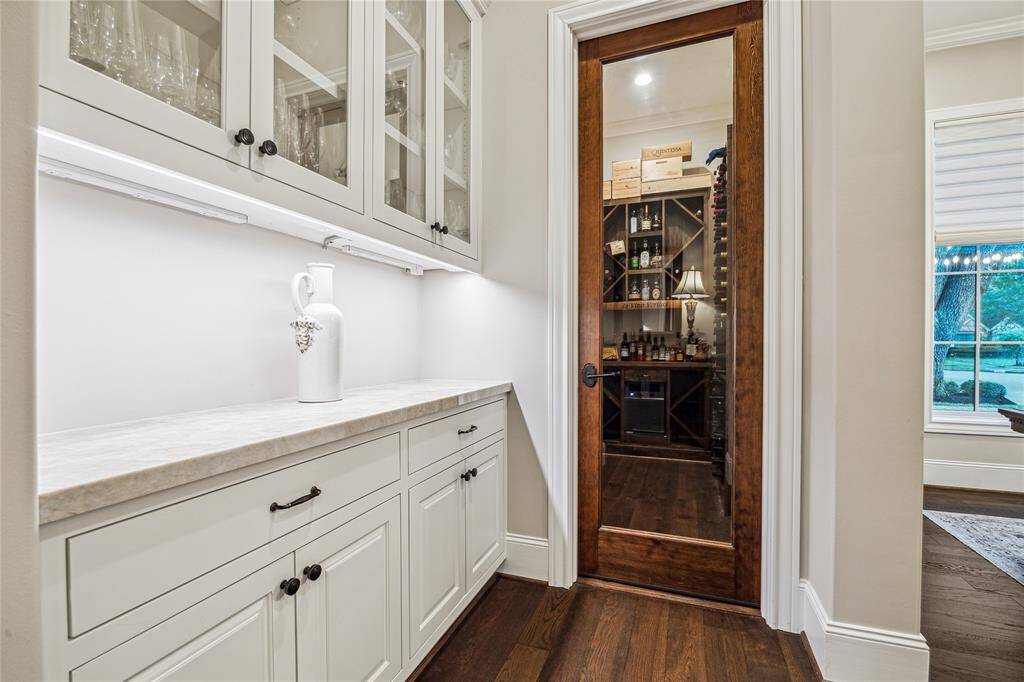 The butlers pantry is a functional transition space featuring custom cabinetry, offering seamless access from the formal dining to the kitchen. It also connects directly to the temperature-controlled wine room for effortless entertaining flow.