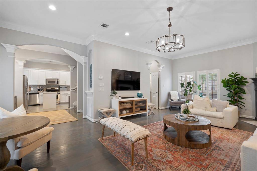 Another view of the living room looking towards kitchen and hallway with half bath and storage closet. Hallway leads to the dining room. The space creates a circle around the staircase.