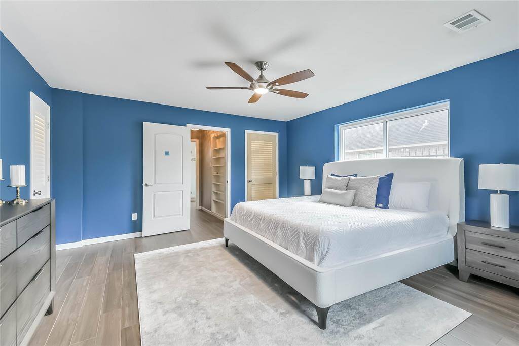 This view of the primary bedroom shows the built in bookcase in the hall leading to the bathroom. When you're in the hall - look up and see the sparkling crystal lighting fixture.