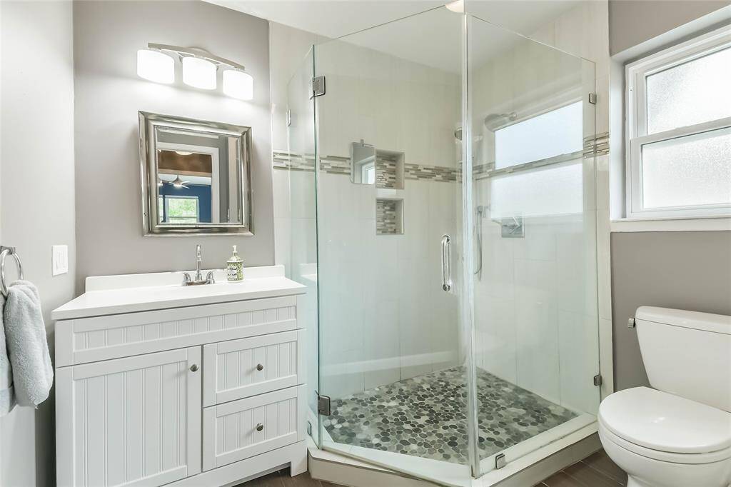 The updated primary bath features an oversized shower with pebble floor (the flat kind!) Frameless shower surround, mosaic tile insets.