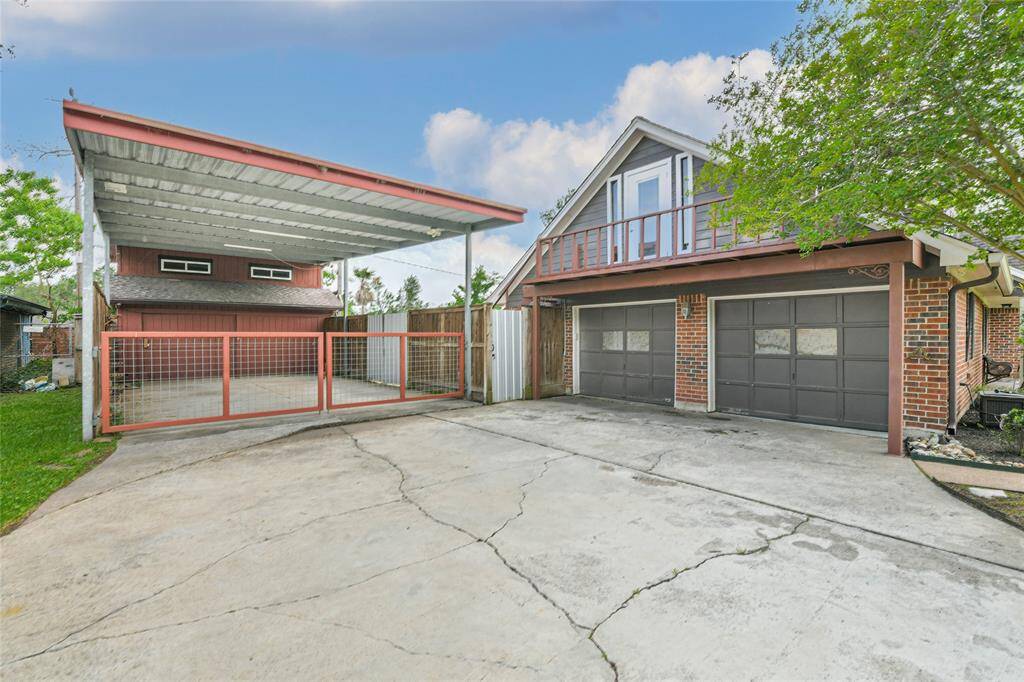 Plenty of driveway space leads to the over-sized 2 car garage. This view shows you the gated entrance to the carport - fit for a large RV or boat and the barn. The bottom portion of the barn can also, add 2 more garage spaces.