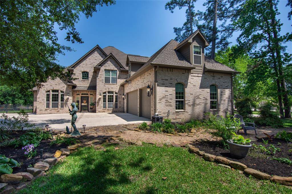 Spacious brick house with a three-car garage and a large driveway. It features a well-maintained lawn, mature trees, and a welcoming entrance, perfect for family living in a serene neighborhood.