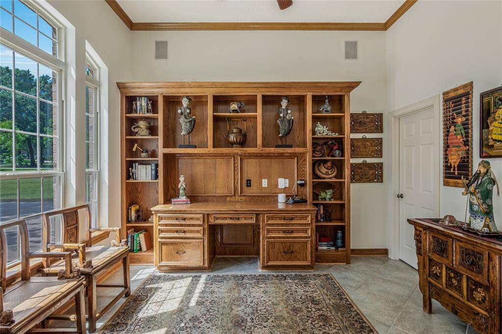 This room features a bright, spacious study with large windows, built-in wooden shelves and desk, and elegant decor. Ideal for a home office or reading nook.