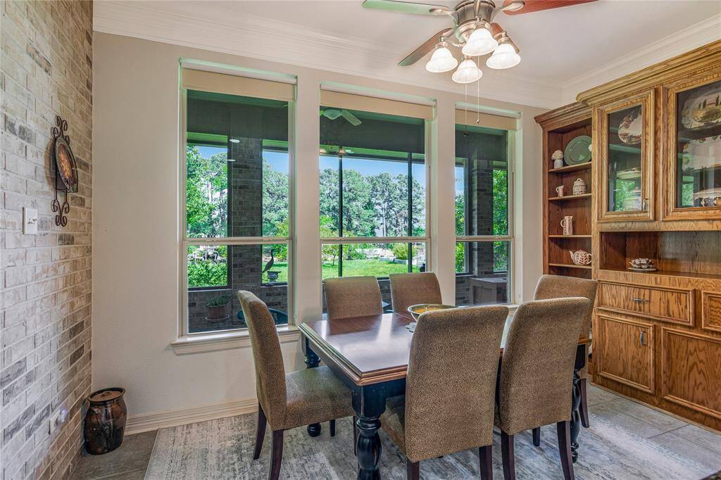 The eat in kitchen features large windows with a view of a lush green backyard.