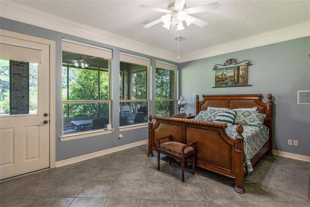 This spacious primary bedroom features large windows offering abundant natural light and views of lush greenery, creating a cozy and inviting atmosphere.
