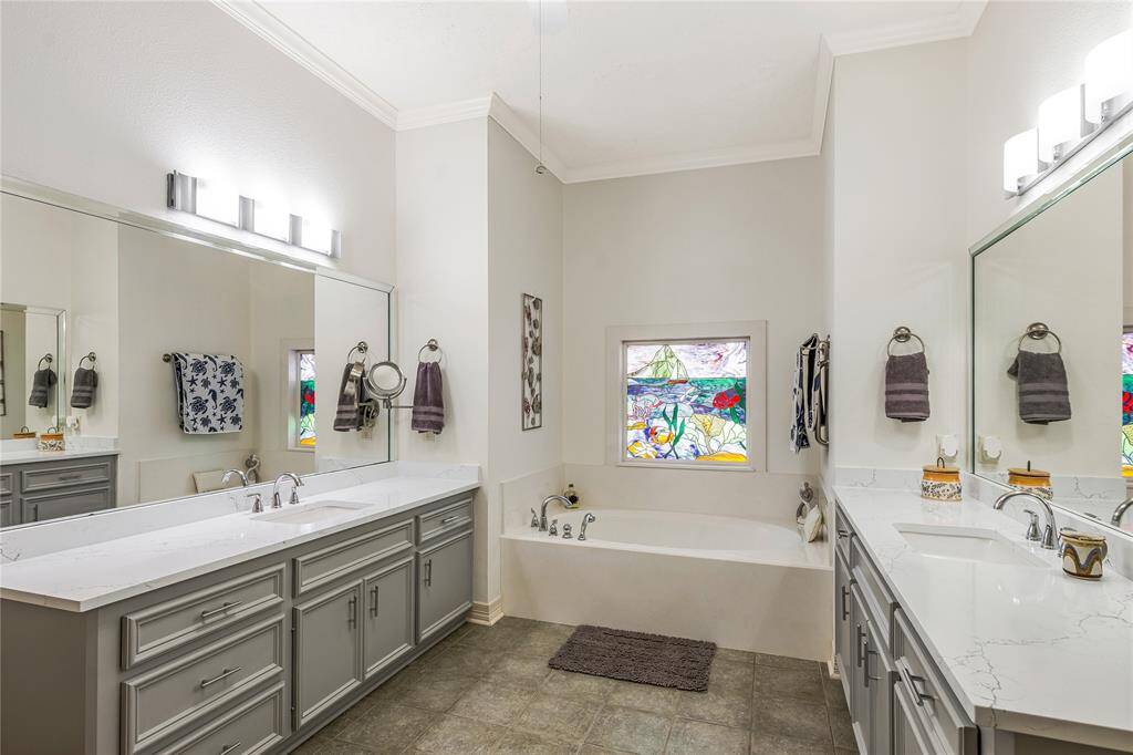 The primary bathroom features a modern design with a large vanity, dual sinks, and ample storage. It includes a glass-enclosed shower with elegant tile work and a separate bathtub.