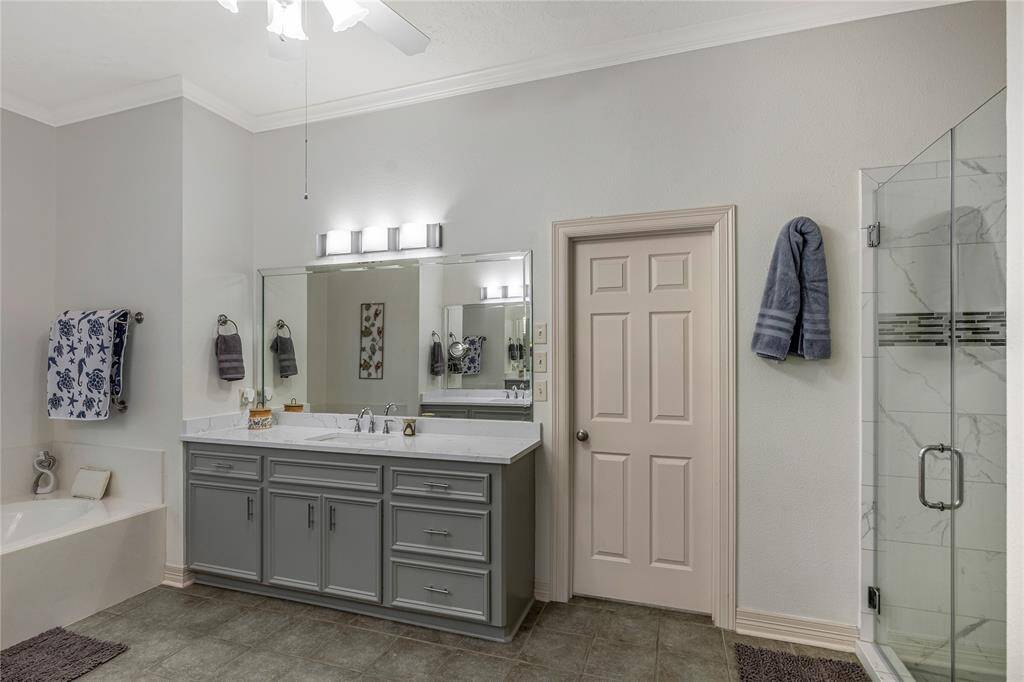 The spacious primary bathroom features dual sinks with ample cabinetry, a large soaking tub, and elegant stained glass windows, offering a blend of luxury and functionality.
