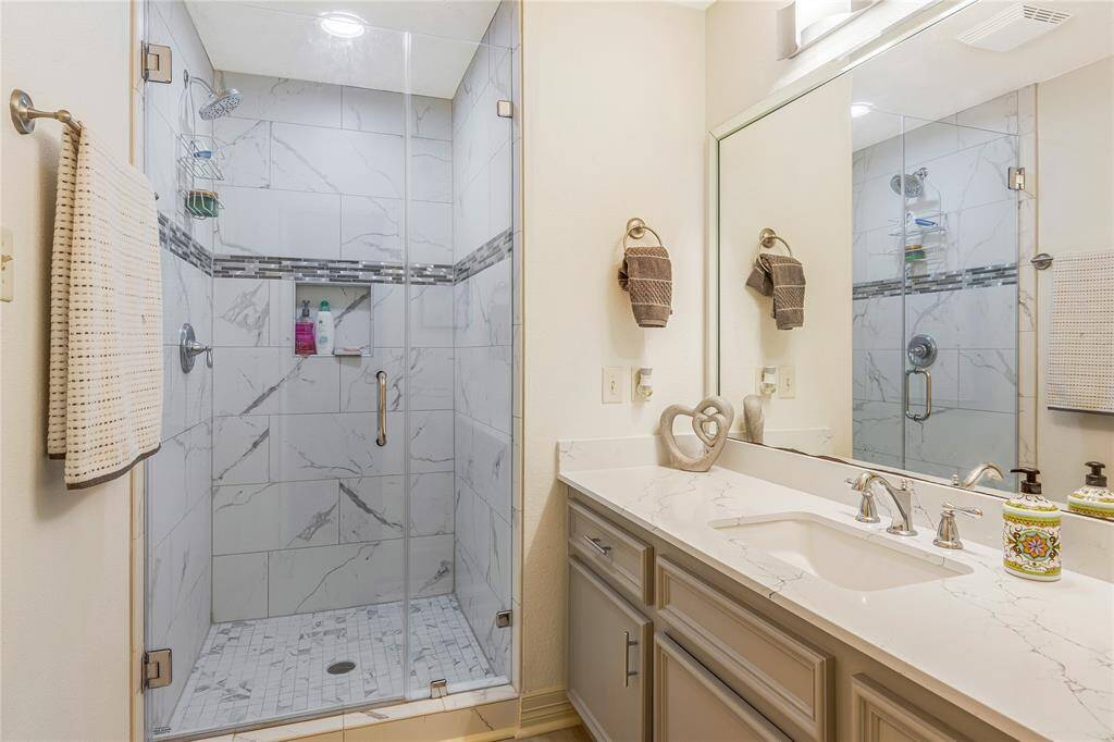 Bathroom with a clean, modern design. Features a white bathtub with polished fixtures, a toilet, and upper gray cabinetry.