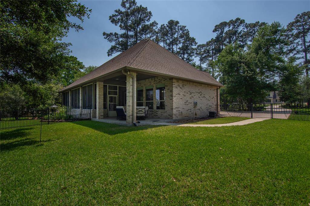 This photo showcases a charming brick home with a spacious screened-in porch, surrounded by a lush, well-maintained lawn and mature trees, offering privacy and tranquility.