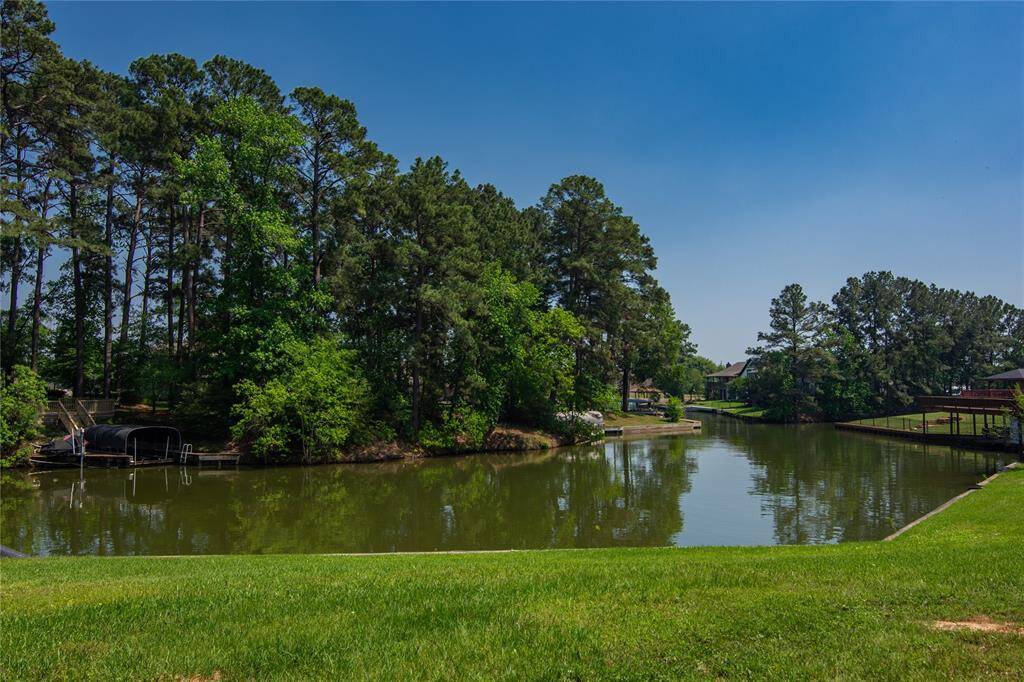 This photo showcases a serene waterfront setting with lush greenery and tall trees lining a calm, narrow waterway.
