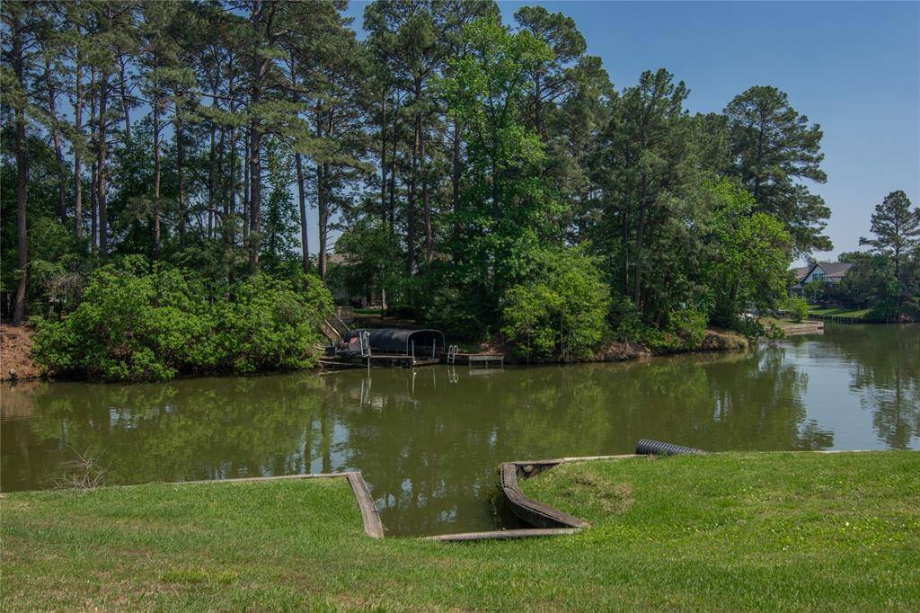 This serene photo showcases a quiet waterfront view with lush greenery and tall trees lining the banks. The calm water offers a peaceful setting, perfect for a home with tranquil surroundings.