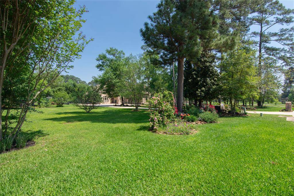 Spacious, lush green yard with mature trees and vibrant flower beds, offering a serene and picturesque setting for a home.