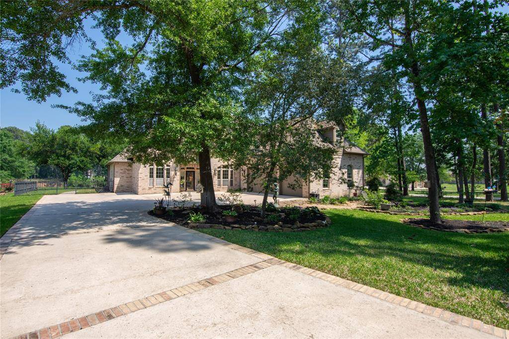This photo captures a long, winding driveway bordered by vibrant greenery and mature trees, offering a peaceful and inviting approach to the property. Beautiful flower beds and meticulous landscaping further elevate the curb appeal.