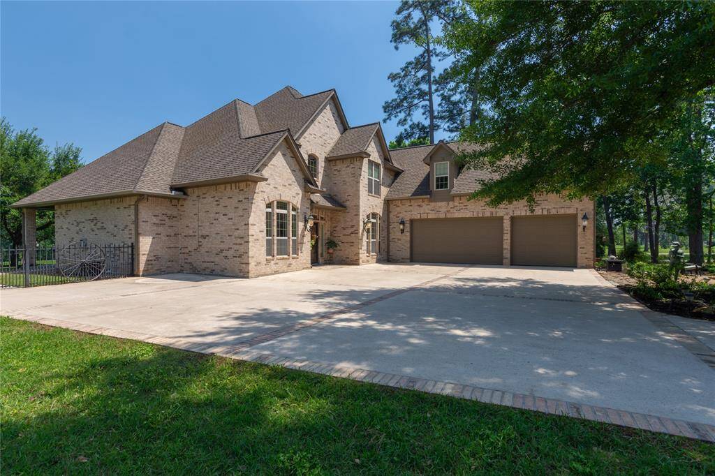 This beautiful two-story brick home features a charming exterior with large windows and a three-car garage. Surrounded by lush landscaping and mature trees, it offers a spacious, inviting front yard with a stone path and well-maintained garden, perfect for a serene living experience.