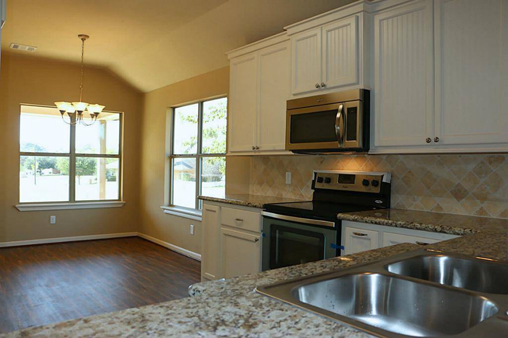 Breakfast room with tons of windows. Open breakfast and kitchen with laminate flooring.