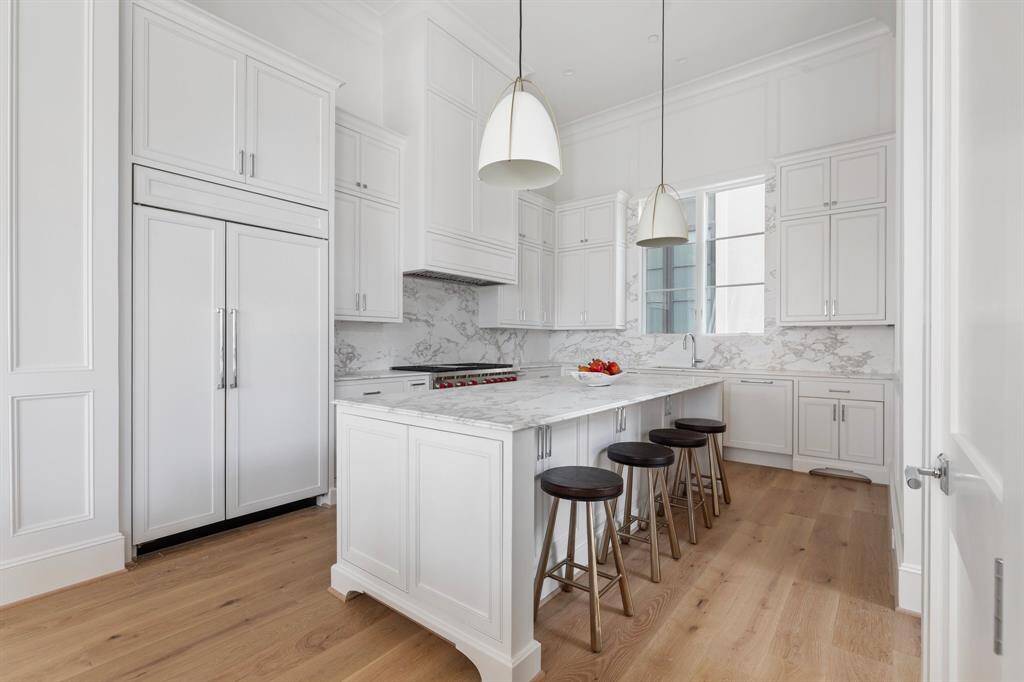 A chef’s dream, this kitchen features a 10' marble island, floor-to-ceiling cabinetry, and designer lighting.