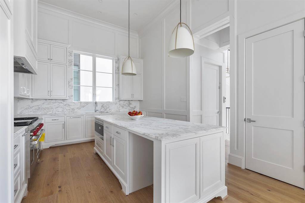 An abundance of natural light pours through expansive windows into this open kitchen enhanced by designer touches and rich architectural elements that elevate everyday living.