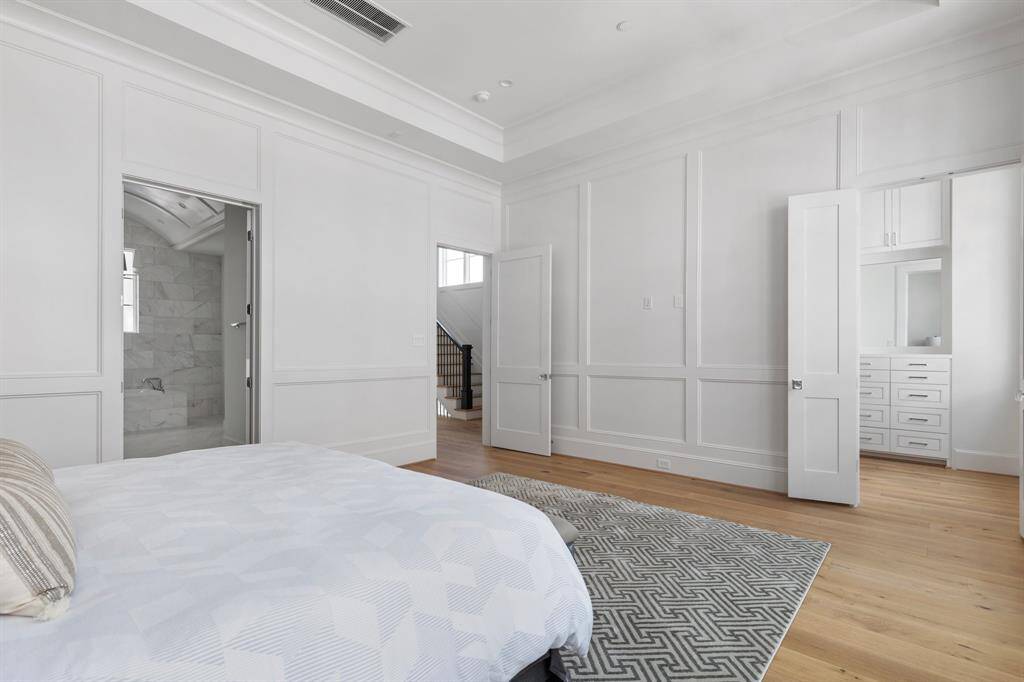 The level of superior craftsmanship is clear in this bedroom, from the custom wainscoting to the high ceilings and thoughtfully placed windows, creating a space that feels both expansive and intimate.
