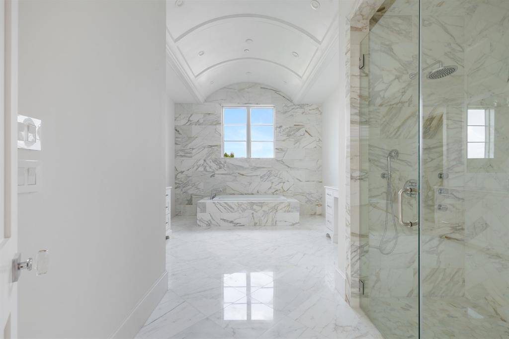 The standout features of the primary spa-suite include extensive marble cladding and a stunning barrel vault ceiling with designer chandelier.