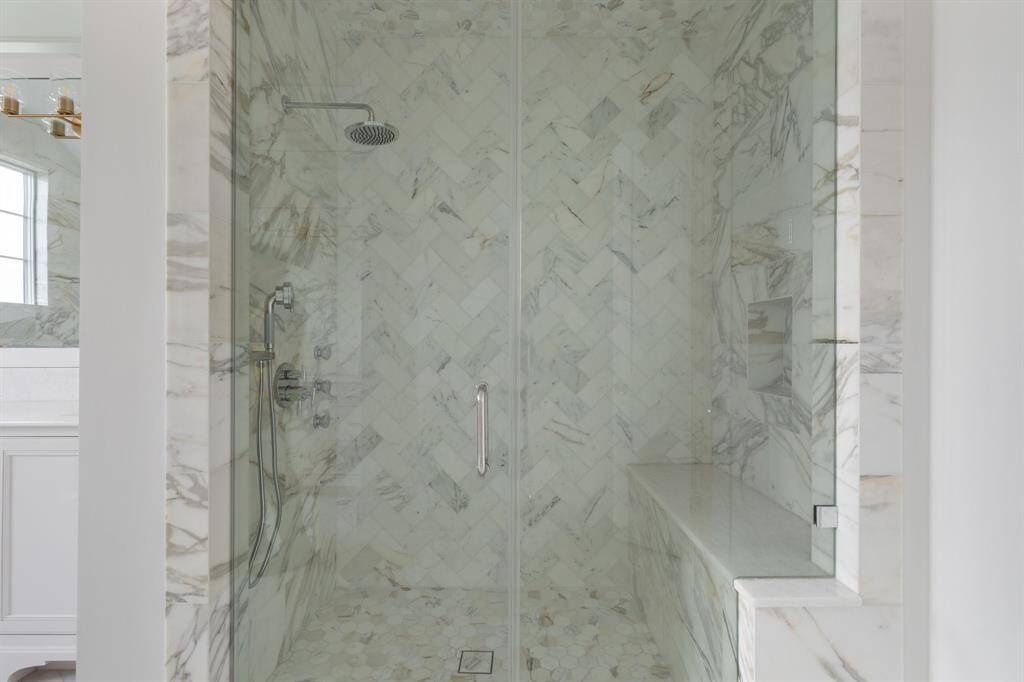 The spa-inspired retreat is complete with a frameless marble shower with over head rain shower, handheld sprayer, body spray jets and bench seating.