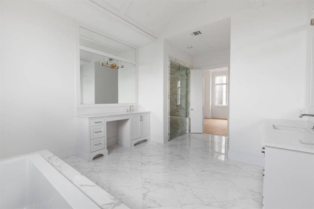 Dual vanity areas feature marble countertops, statement lighting, and furniture style built in cabinetry.