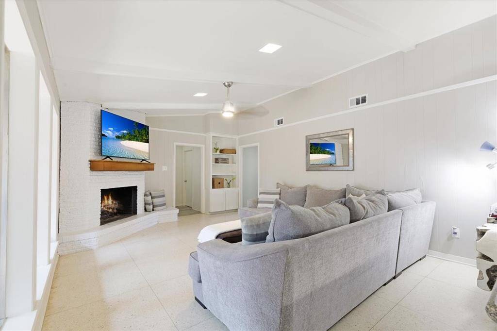 The family room features new paint, a statement brick fireplace, crown molding and built in shelving.