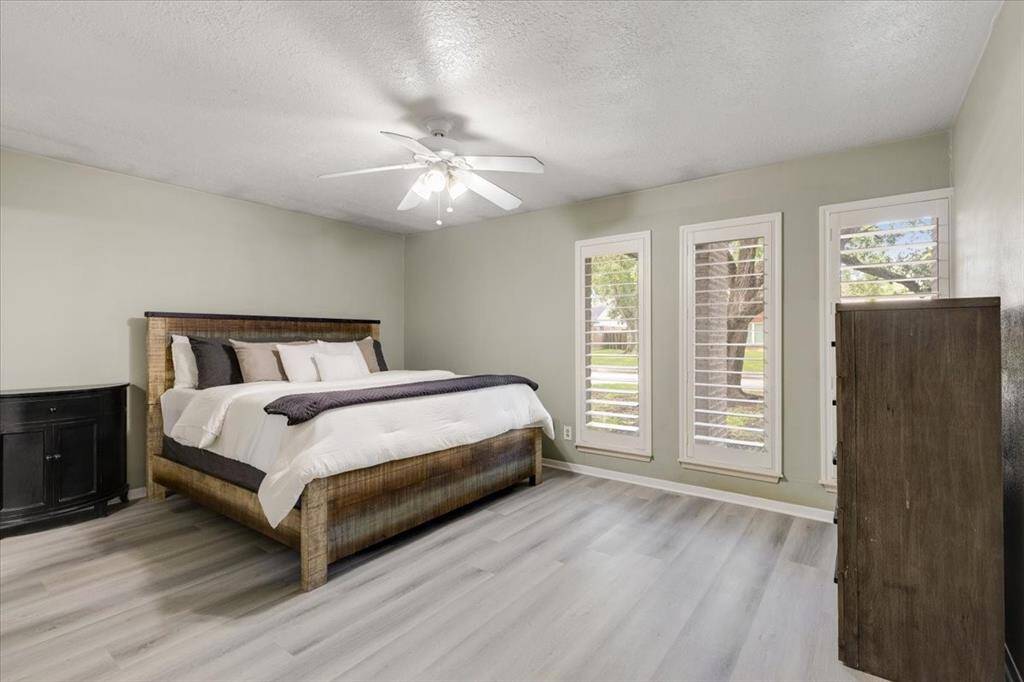 The primary bedroom is spacious and updated with new flooring, paint and plantation shutters on three large windows, bathing the room in natural light.