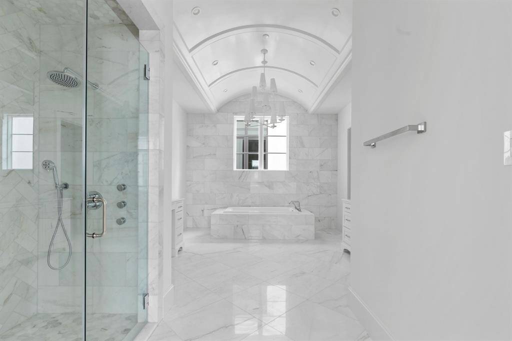 The standout features of the primary spa-suite include extensive marble cladding and a stunning barrel vault ceiling with designer chandelier.