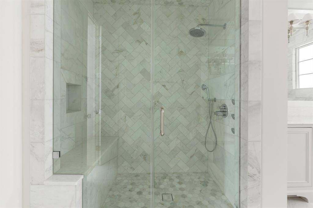 The spa-inspired retreat is complete with a frameless marble shower with over head rain shower, handheld sprayer, body spray jets and bench seating.