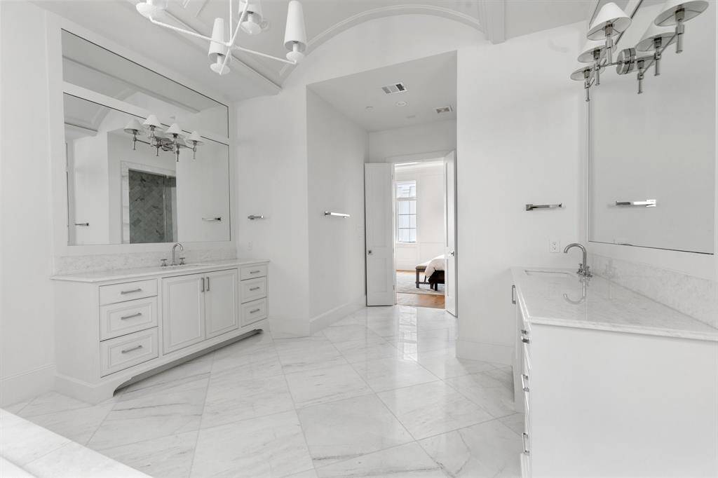 Dual vanity areas feature marble countertops, statement lighting, and furniture style built in cabinetry.