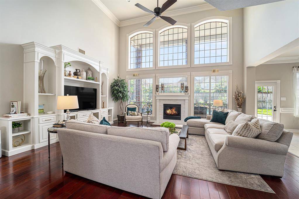 Stunning living room offers an impressive wall of windows, soaring ceilings, and a cozy fireplace—creating the perfect light-filled space to relax or entertain in style.