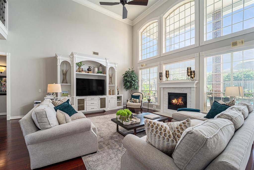 This inviting living room offers the perfect blend of comfort and sophistication with its custom built-ins and expansive windows that overlook the backyard views.