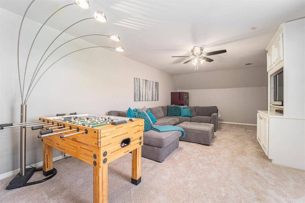 This media room is the ultimate hangout spot, complete with built-in media storage, plush carpeting, and plenty of room for lounging, playing, and entertaining guests of all ages.