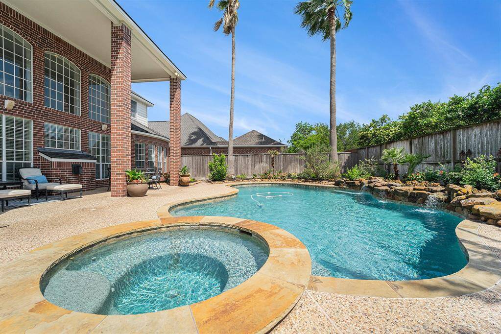 This backyard oasis features a sparking pool with a waterfall and a relaxing spa!